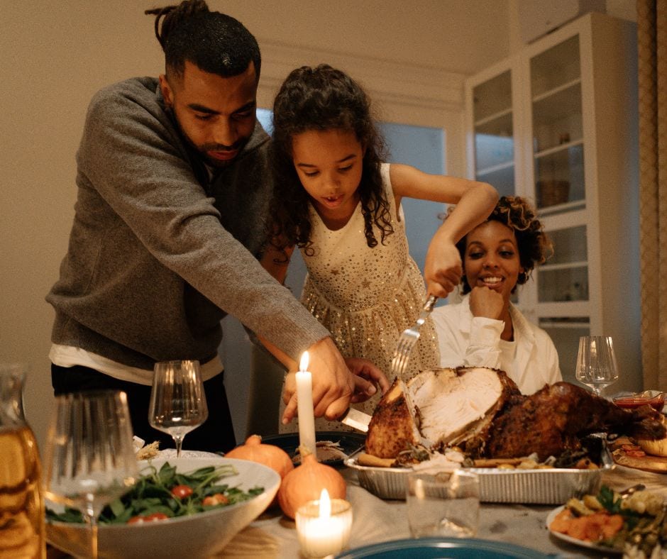 A small family carving meat on the dinner table.