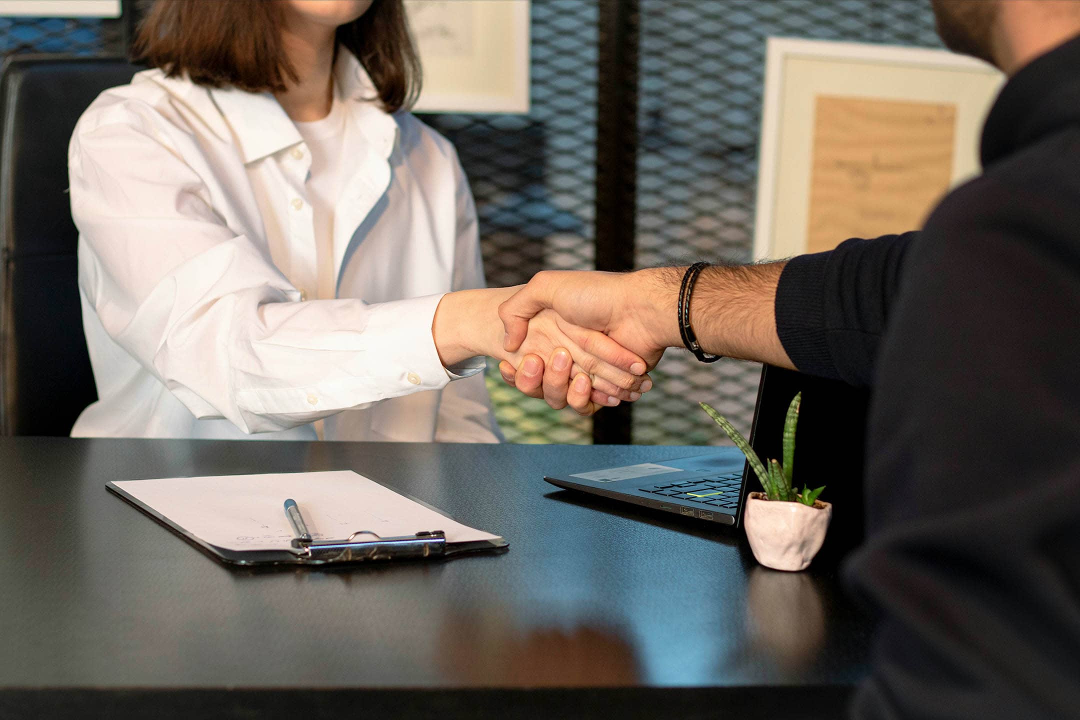 Male and female shanking hands over a table in agreeance.